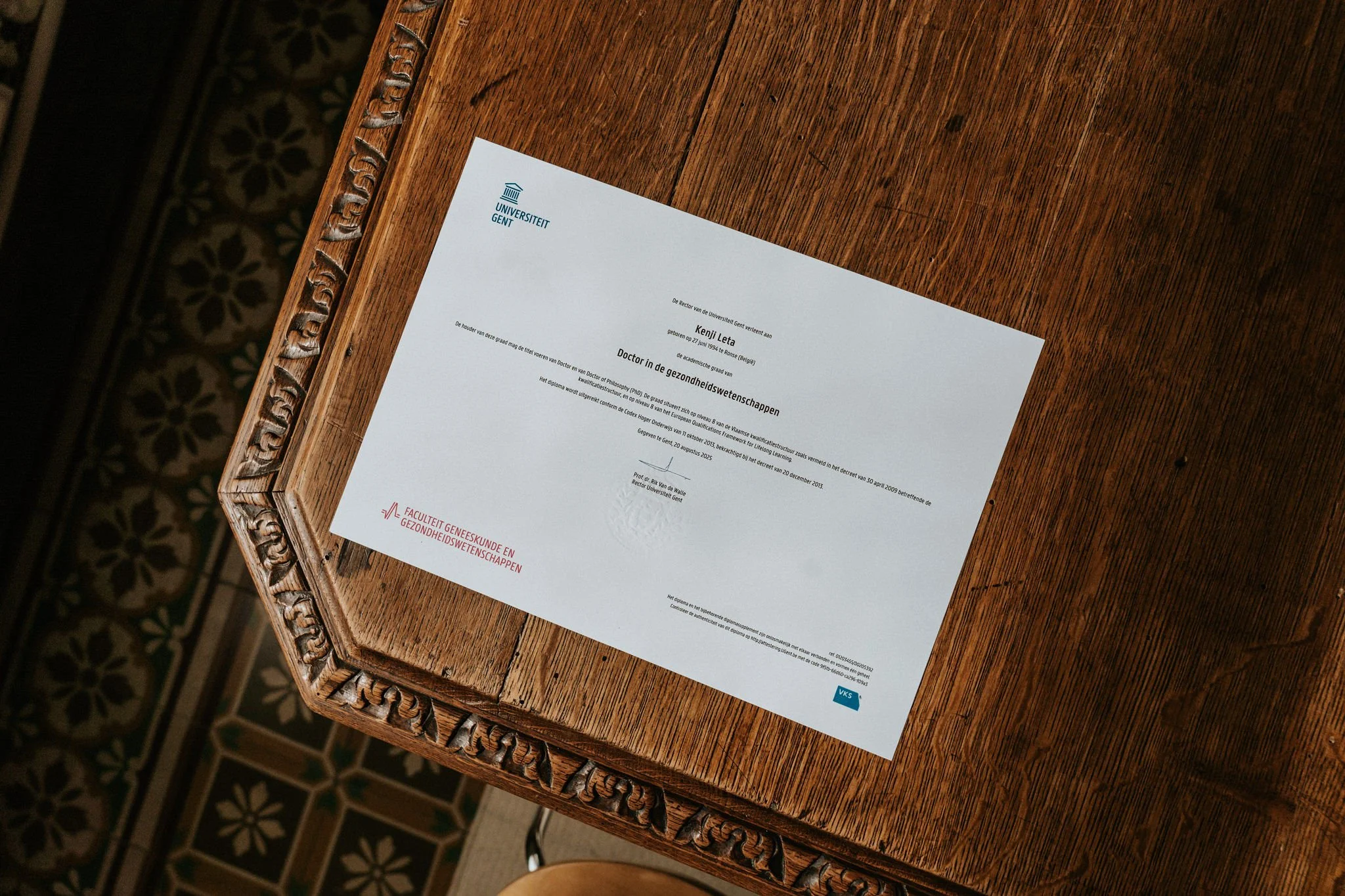 Diploma van de Universiteit Gent op een houten tafel.
