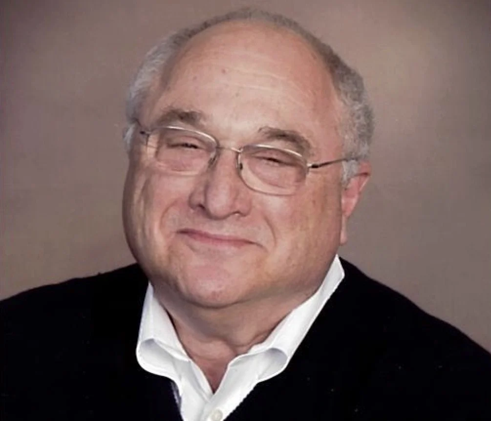 Headshot of Mitch Pearlstein with glasses, graying hair, a white shirt and dark sweater.