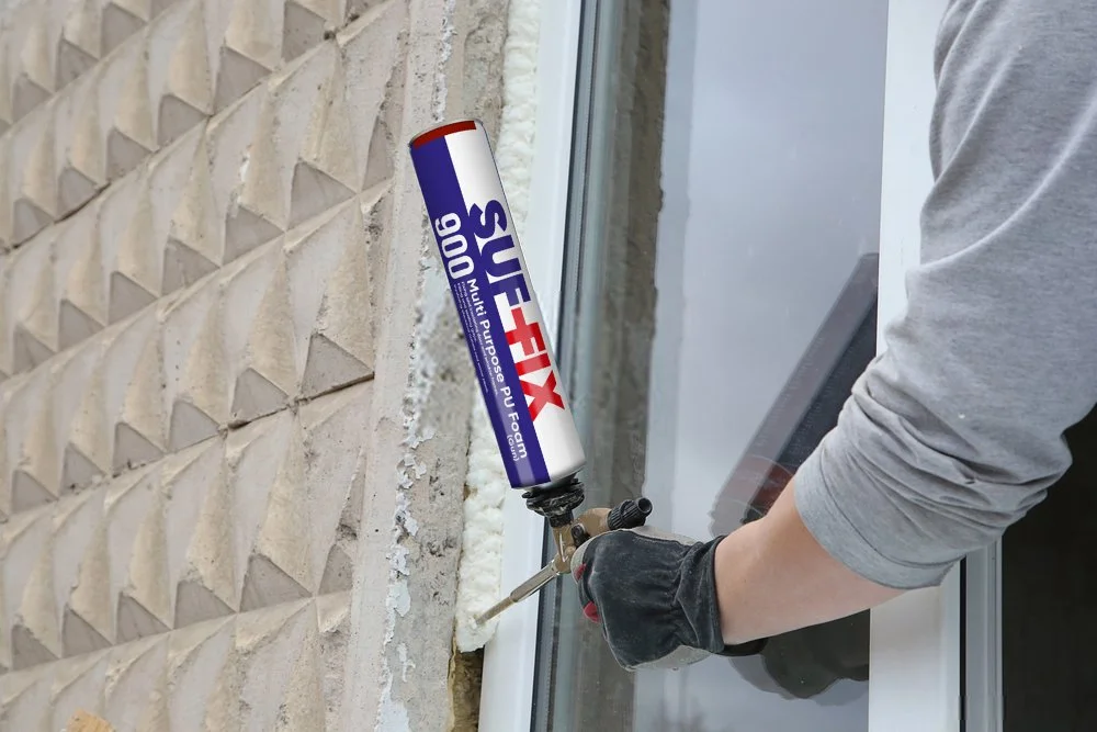 Person applying foam sealant to a gap between a brick wall and a window frame