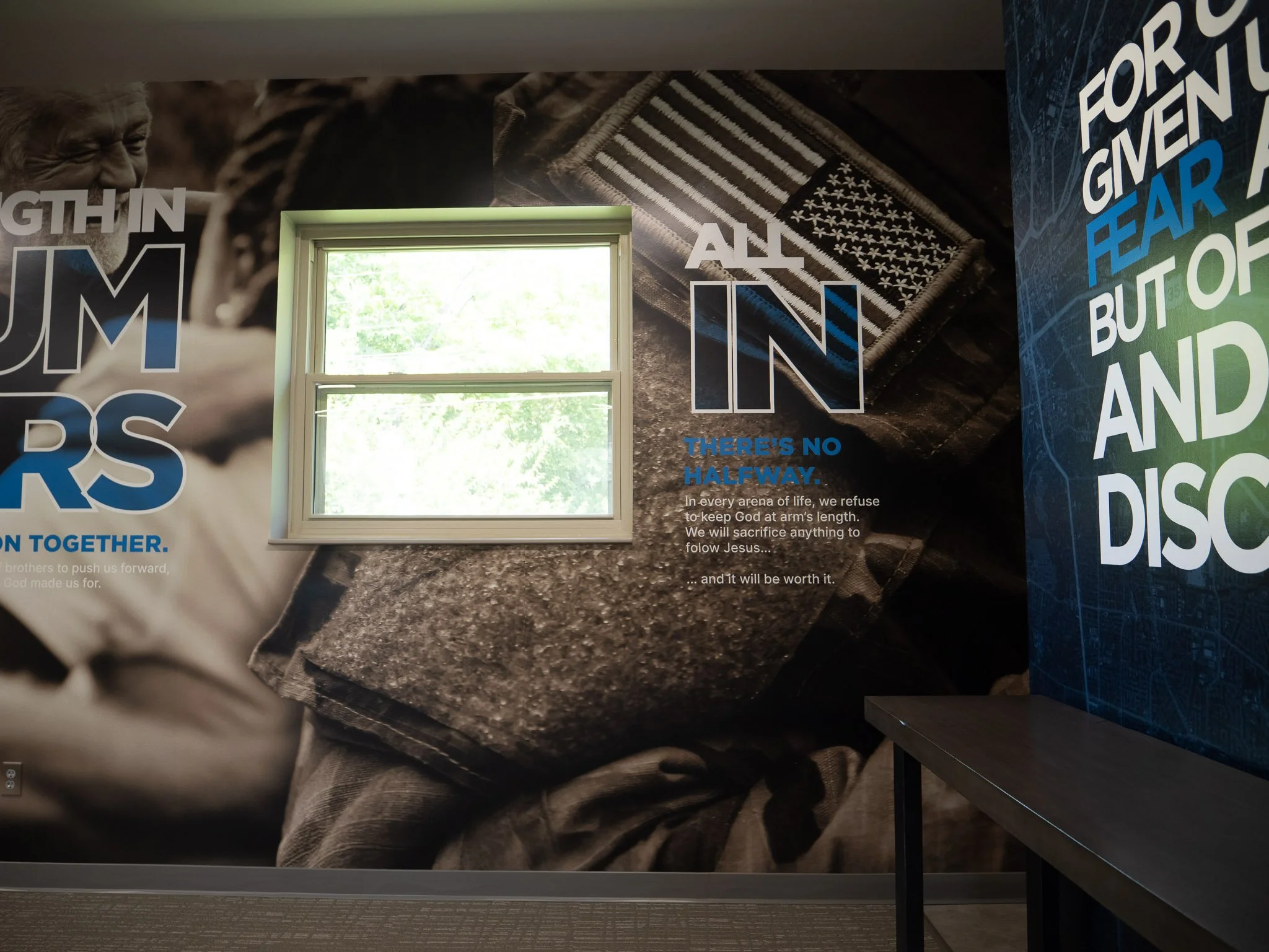 a large wall poster featuring an American soldiers arm and badge with the text "all in" displayed