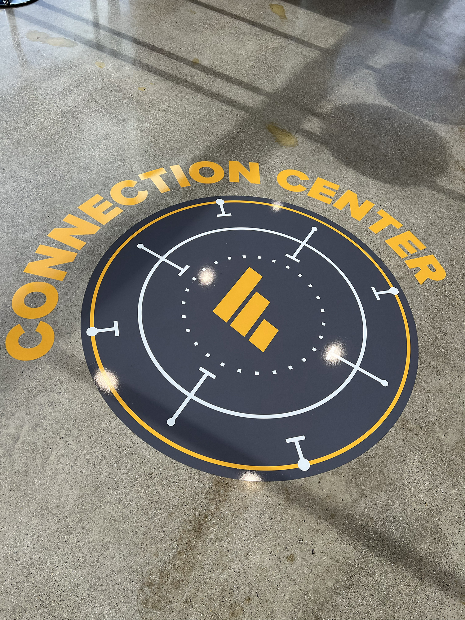 Floor sticker with a hockey puck graphic and the text 'COMMUNICATION CENTER' around it, located on a concrete floor.