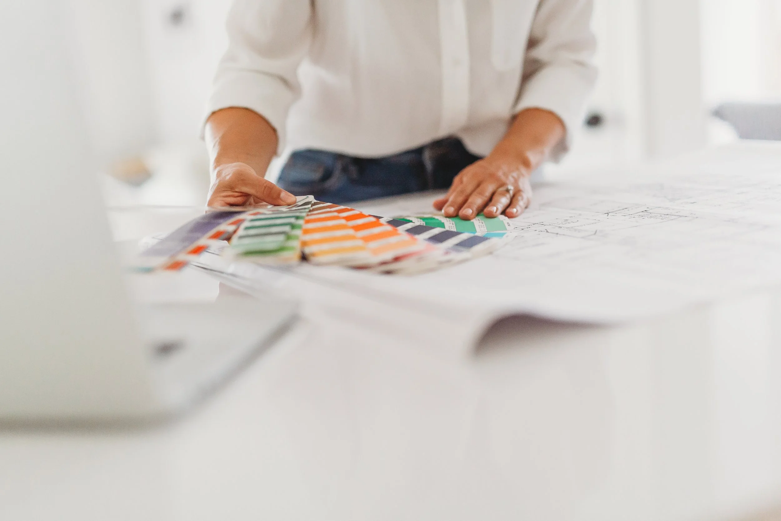 Person wearing a white shirt reviewing color swatches on a table.