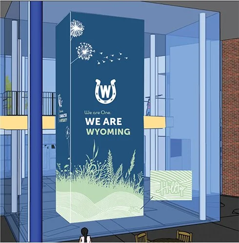 A large glass display promoting Wyoming, featuring a Wyoming logo, fireworks, and grass imagery, with the text 'We Are Wyoming' and 'We are One.'