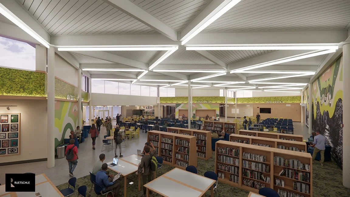 Interior of a modern library with bookshelves, study tables, and people reading or walking around.