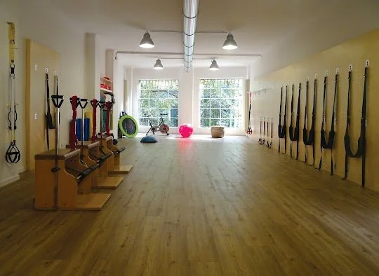 Sala di allenamento con attrezzi da fitness appesi alle pareti e oggetti come palloni e kettlebell sul pavimento