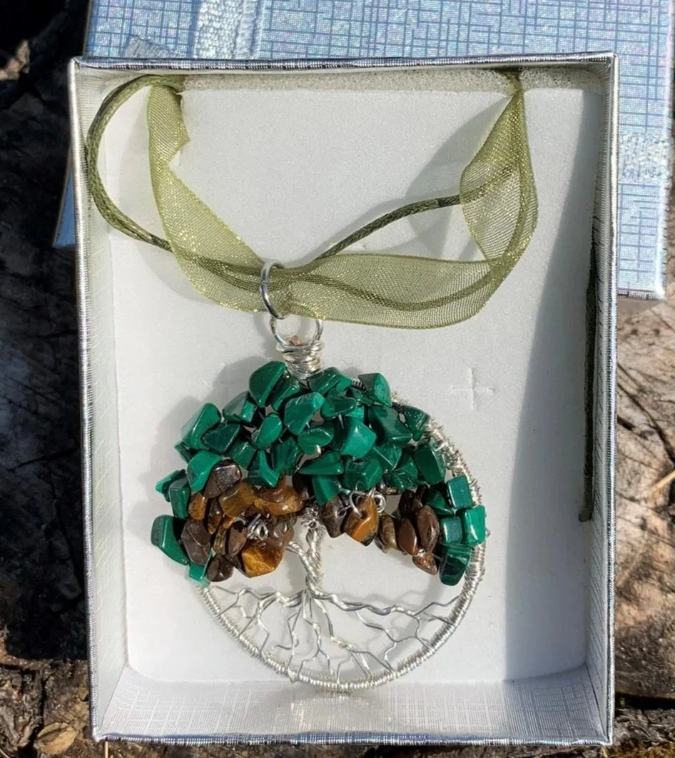 Necklace with a tree of life design made of wire, Malachite and Golden Tiger Eye gemstone chips, wrapped in wire, hanging from a yellow/green ribbon choker in a white gift box.