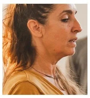 Profil d'une femme avec des cheveux attachés, portant un vêtement beige, dans un environnement intérieur.