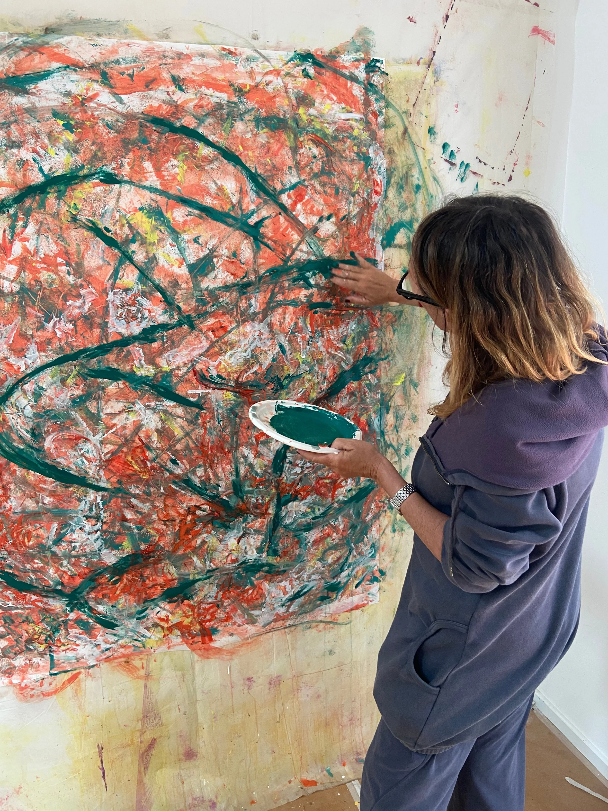 Une femme peint une toile abstraite avec des couleurs vives et des coups de pinceau dynamiques.