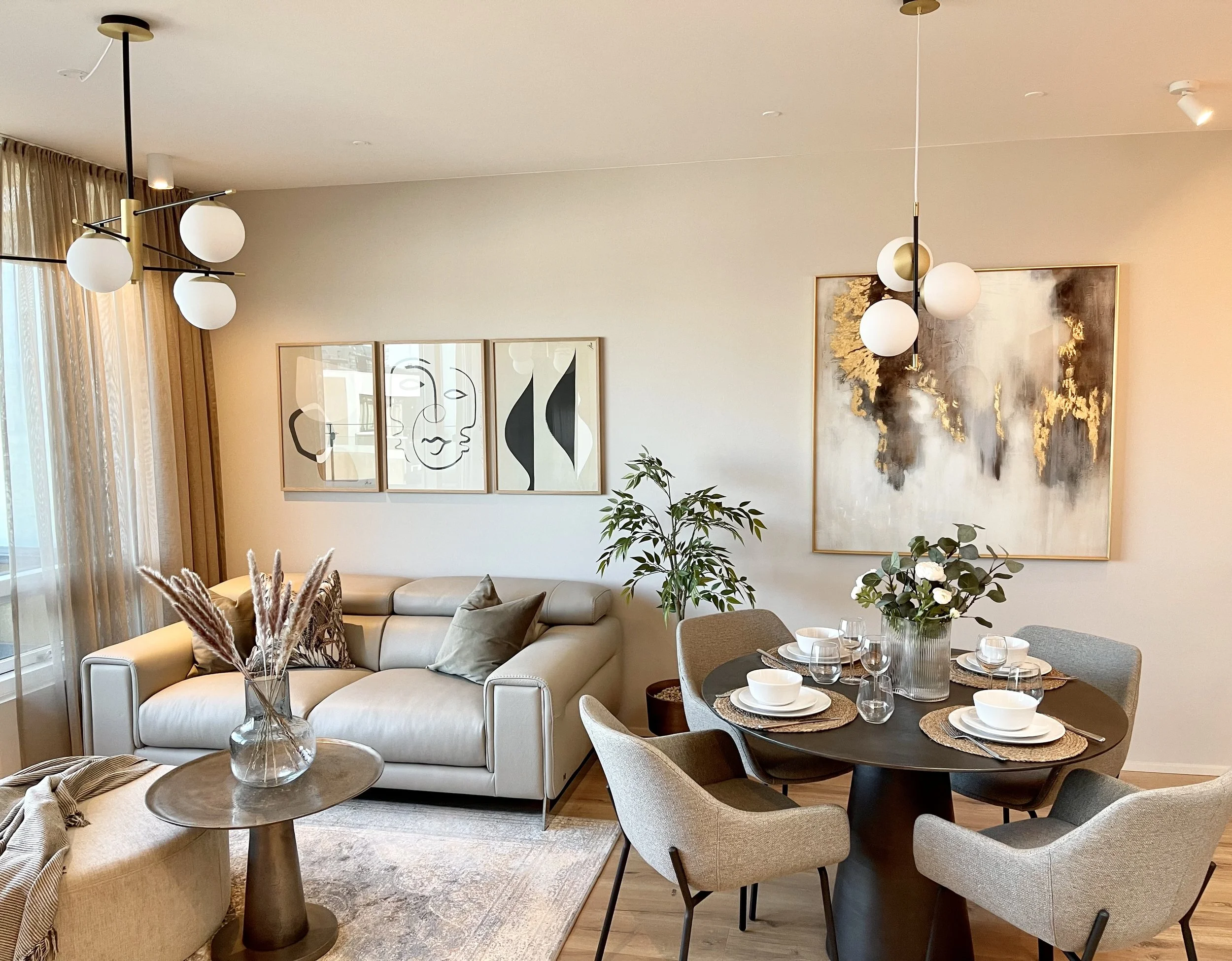 A modern living room and dining area with wall art, plants, and contemporary lighting fixtures.