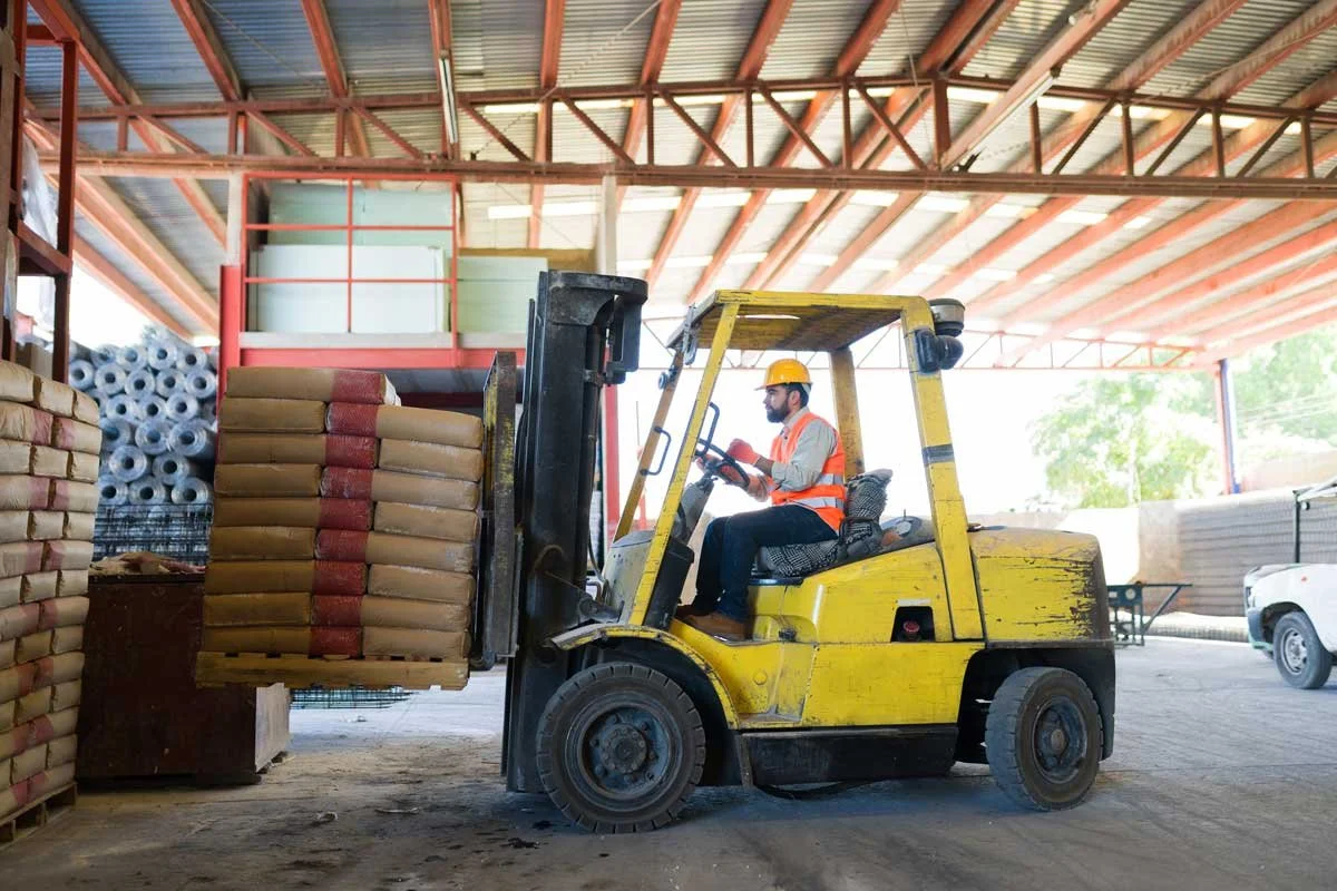 forklift operator lifting heavy building materials on a stringer pallet
