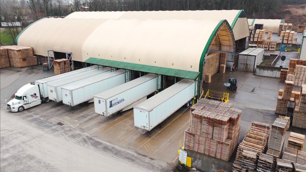 5 trucking trailers parked up to a pallet loading area