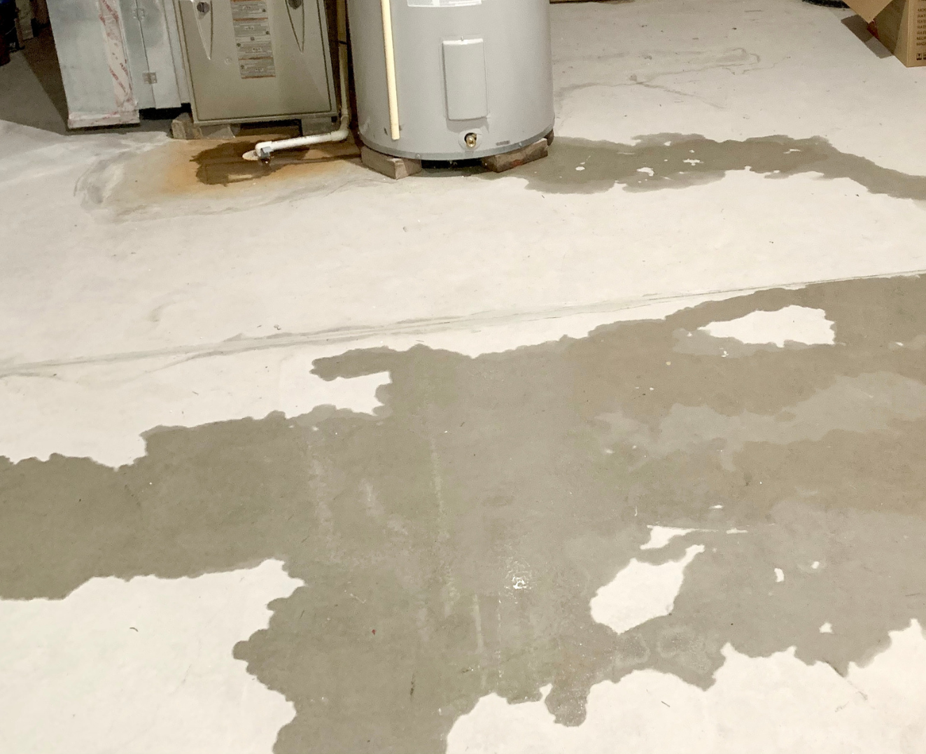 Concrete floor with wet patches and a water heater in the background.