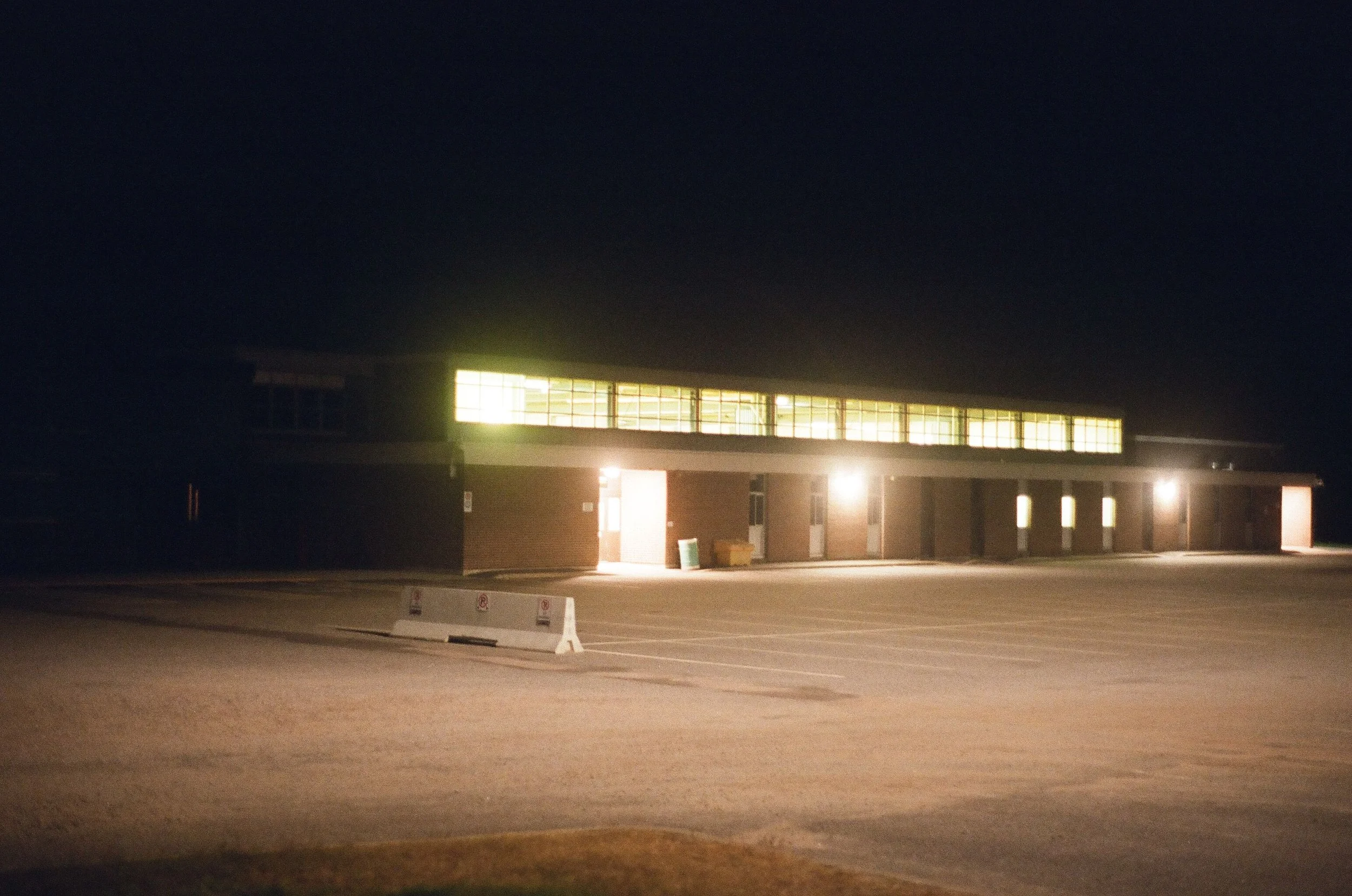 A building at night with large illuminated windows and a dark sky overhead.