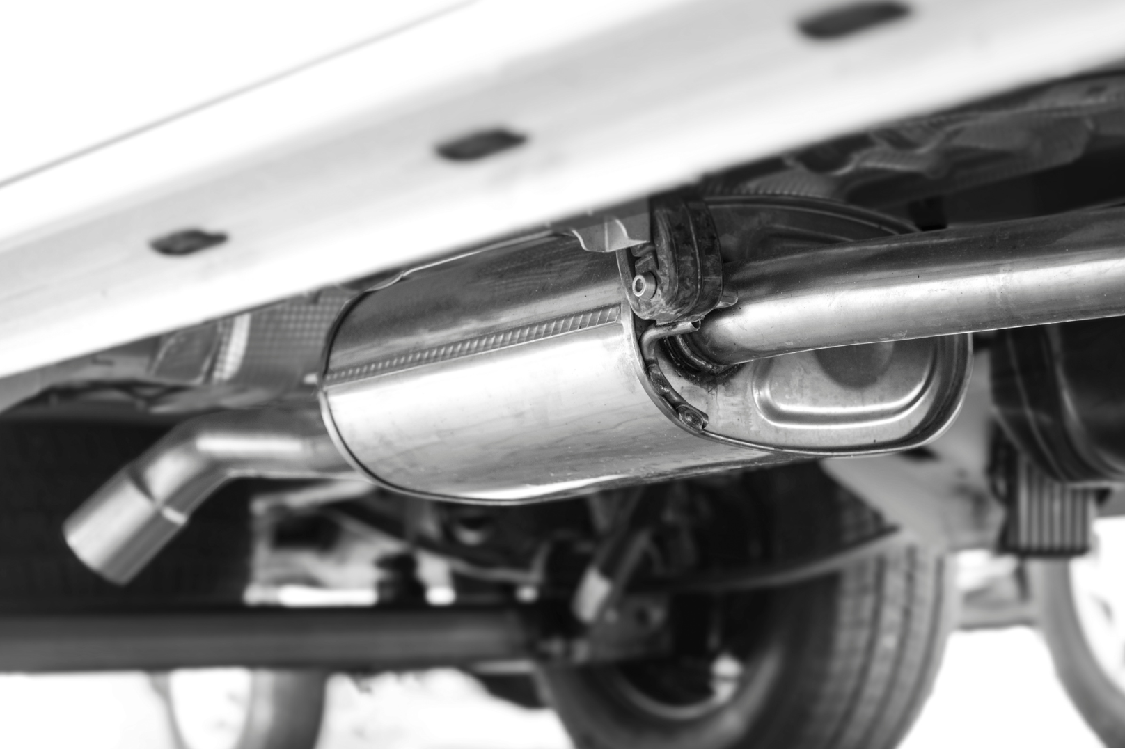 Close-up view of a vehicle's exhaust pipe in black and white.
