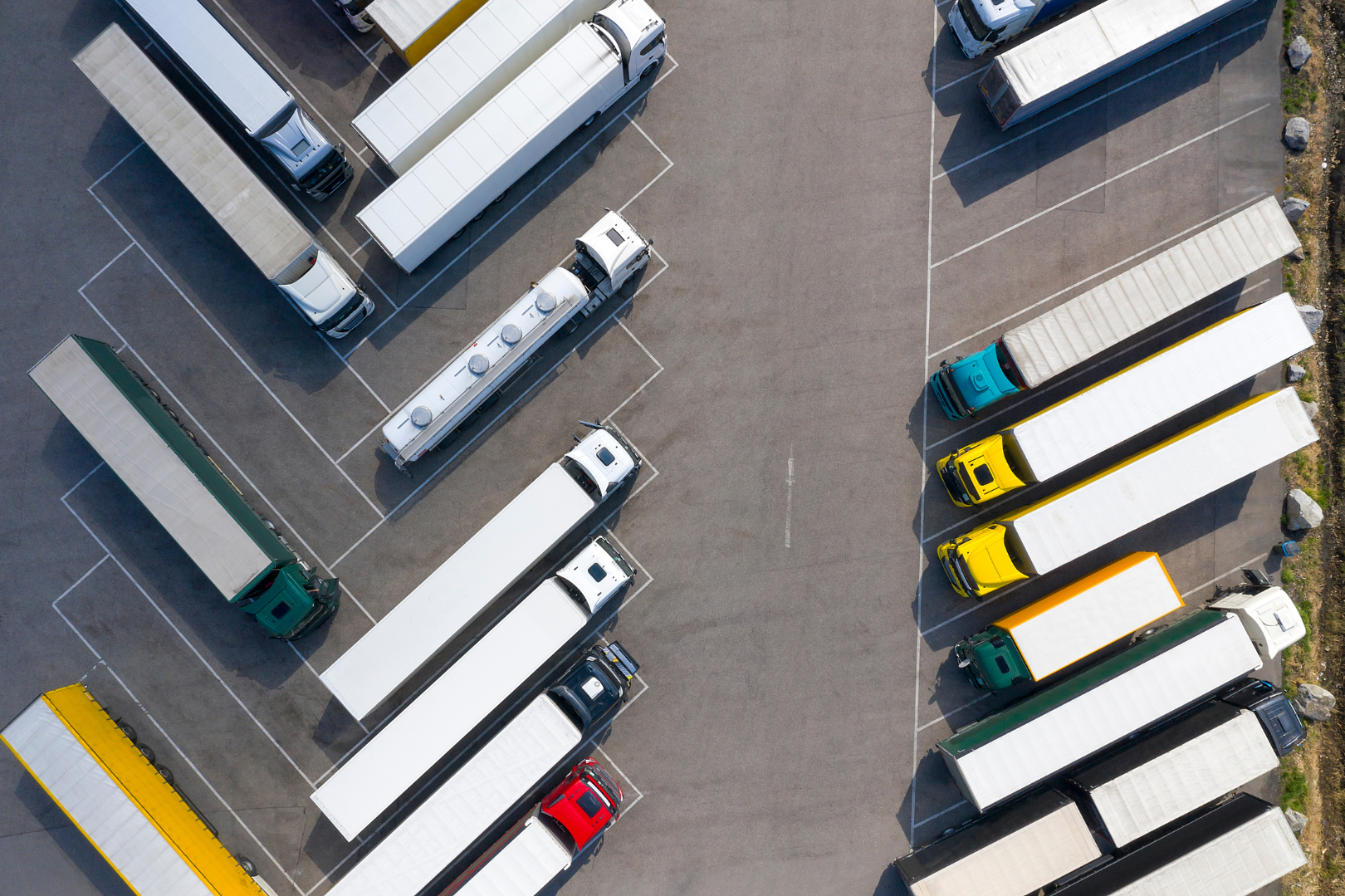 Aerial view of a parking lot with several parked trucks and semi-trailers in designated spaces.