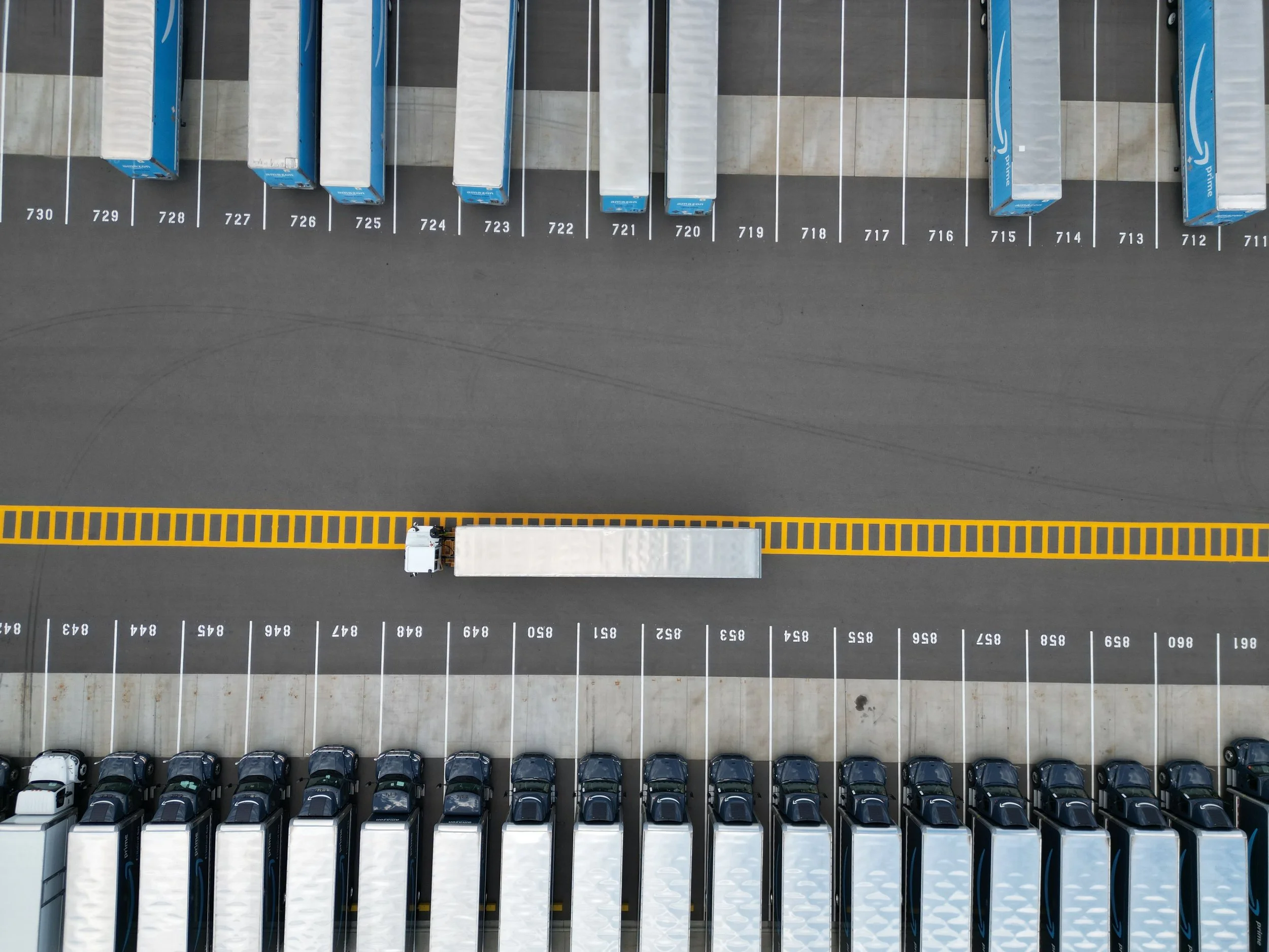Bird's-eye view of a truck lot with multiple semi trucks parked in rows.