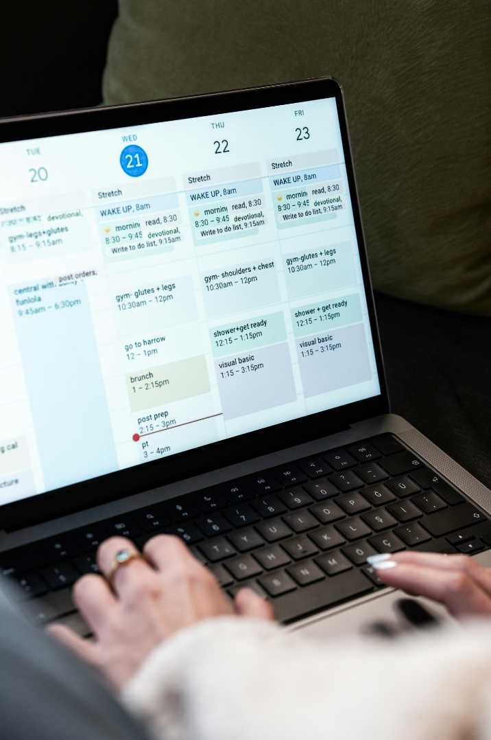Person using a laptop with a weekly calendar schedule displayed on the screen, showing days from Tuesday to Friday with various appointments and activities.