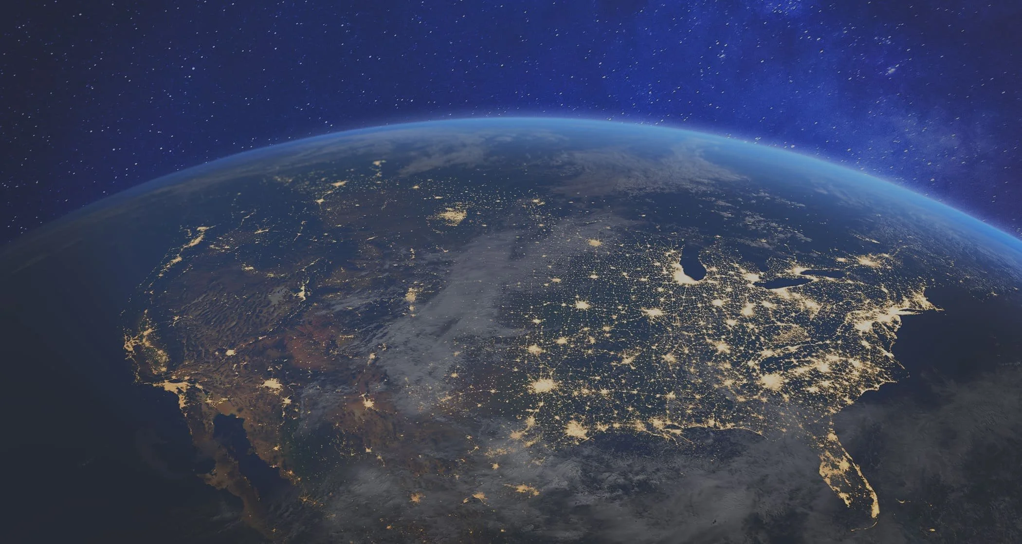Nighttime view of Earth from space showing city lights across North America with the Atlantic Ocean on the right and the Gulf of Mexico at the bottom.