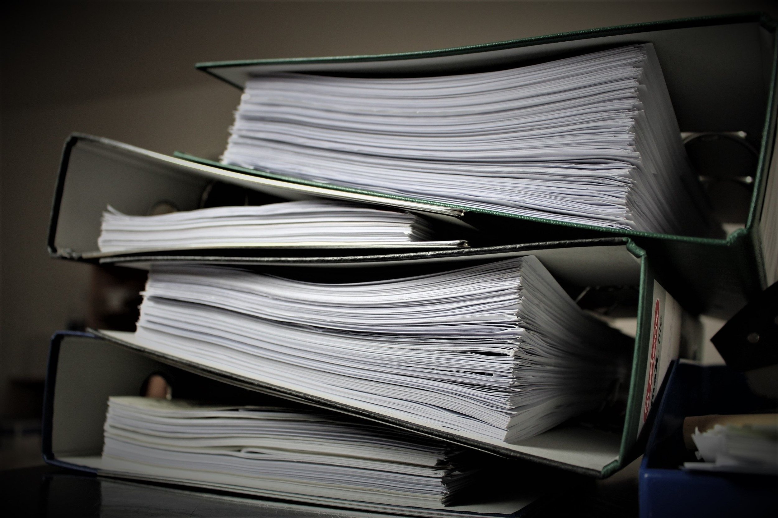 Multiple stacks of binders filled with paper, stacked on top of eachother.