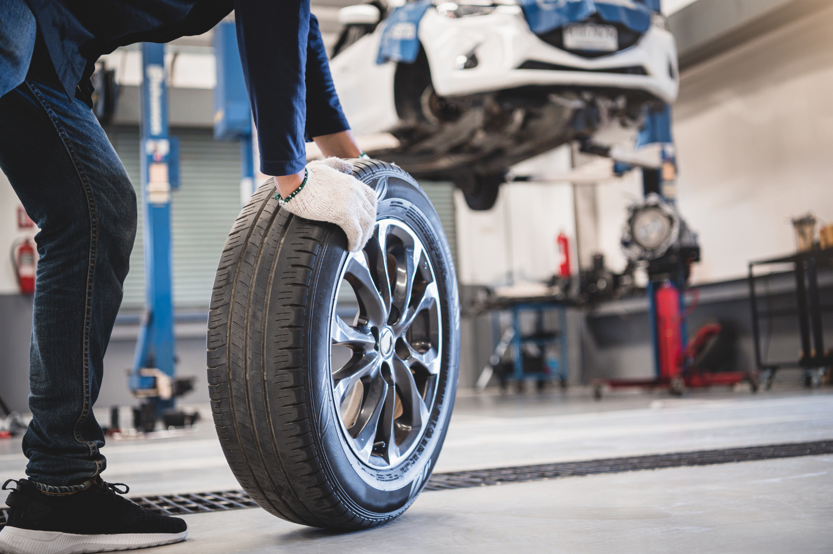 A person changing a car tire in an automotive repair shop.