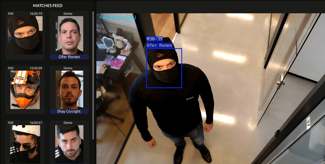 A man wearing a black mask and black beanie looking up at a camera in an elevator, with a surveillance system interface showing recognition of his face and his name as Ofer Ronen.