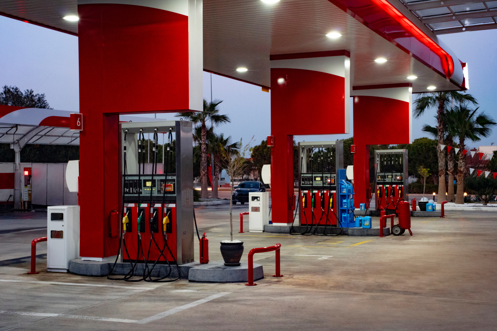 A gas station with multiple pumps in an outdoor setting, with palm trees in the background.