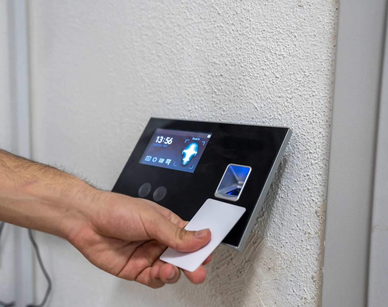 A person using a fingerprint scanner access control device with a card to gain entry.