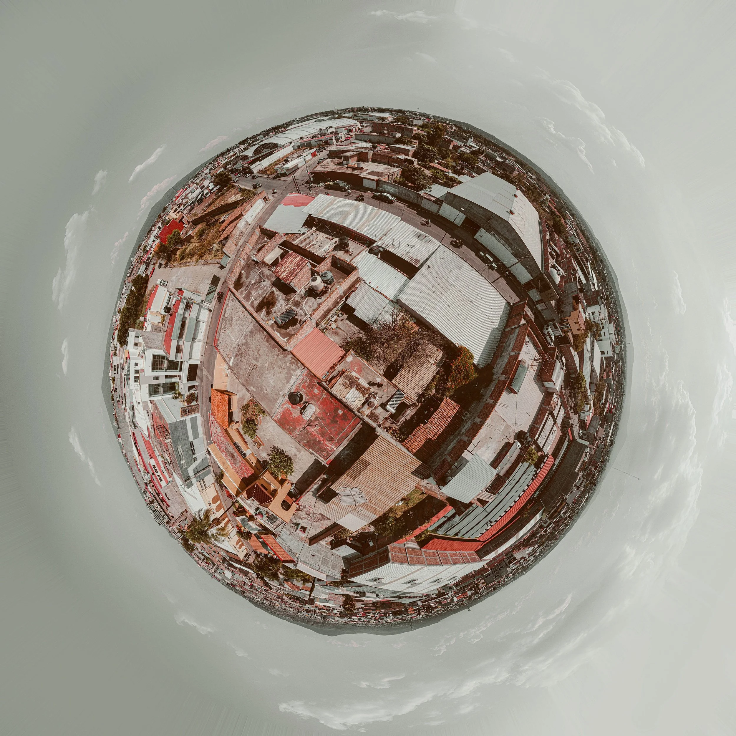 A panoramic, fisheye view of an urban area with buildings, roads, and vehicles, creating a spherical effect.
