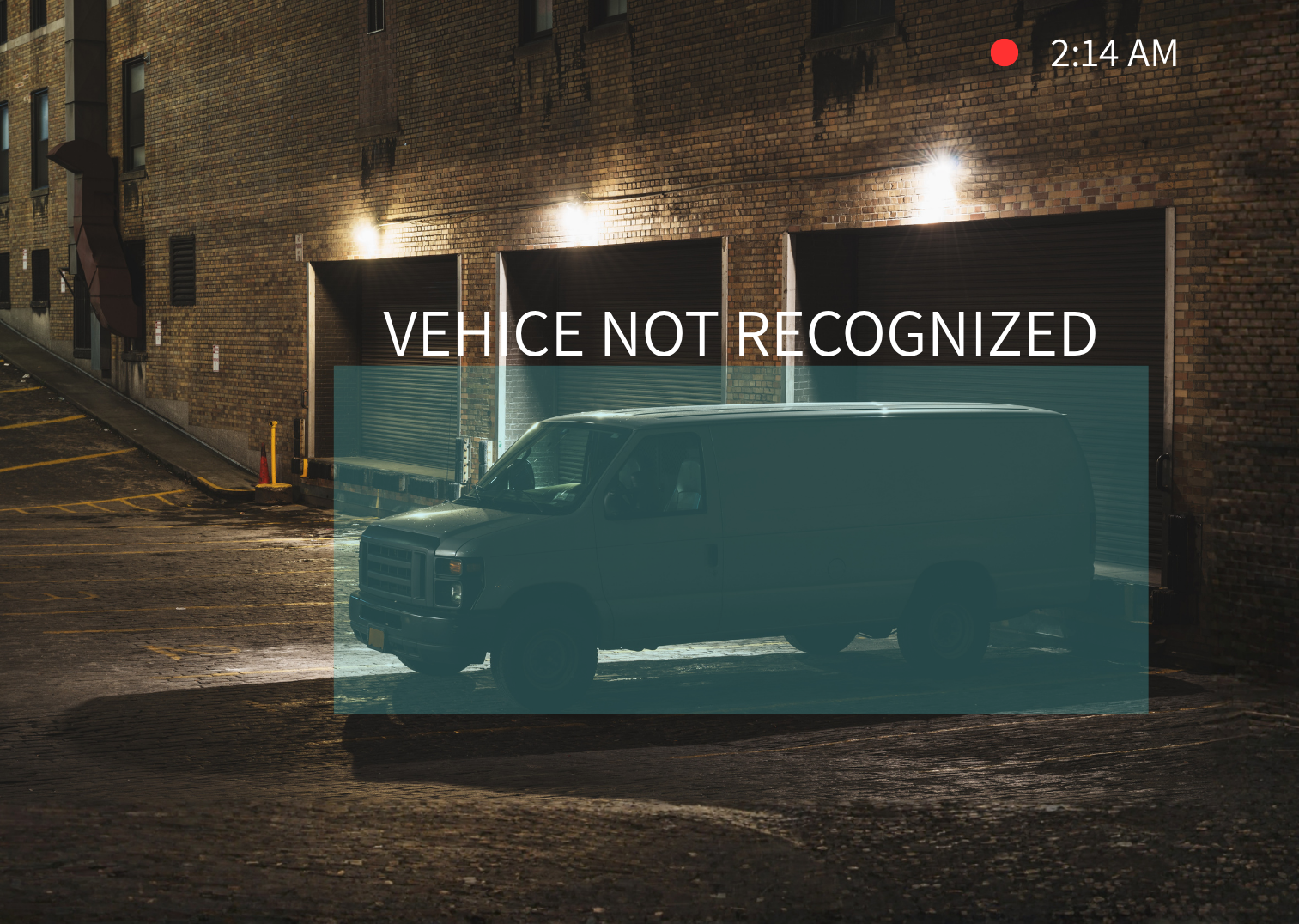 A nighttime city street scene with a black van parked in front of a brick building with three closed loading bay doors. The street is wet, and there are yellow parking lines. The image shows the time as 2:14 AM, with a red recording indicator. Overlaid text says 'VEHICLE NOT RECOGNIZED'.