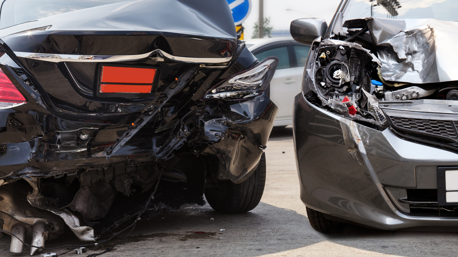 Two damaged cars after a collision, one black and one gray, with significant front-end and rear-end damage.