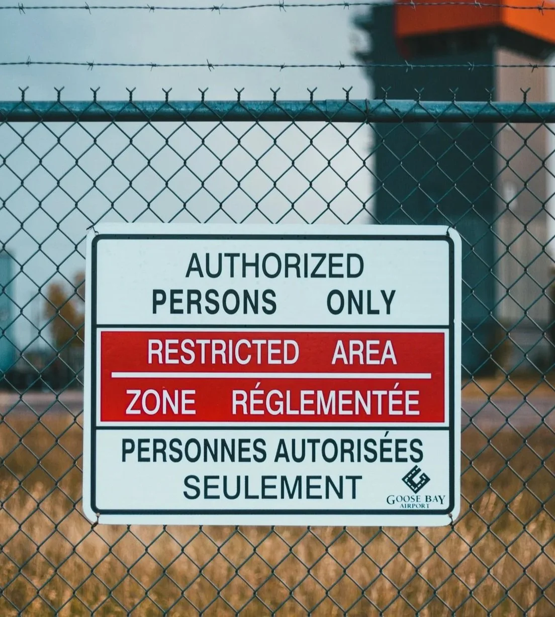 A sign on a chain linked fence with barbed wire reading, 'Authorized Persons Only.'