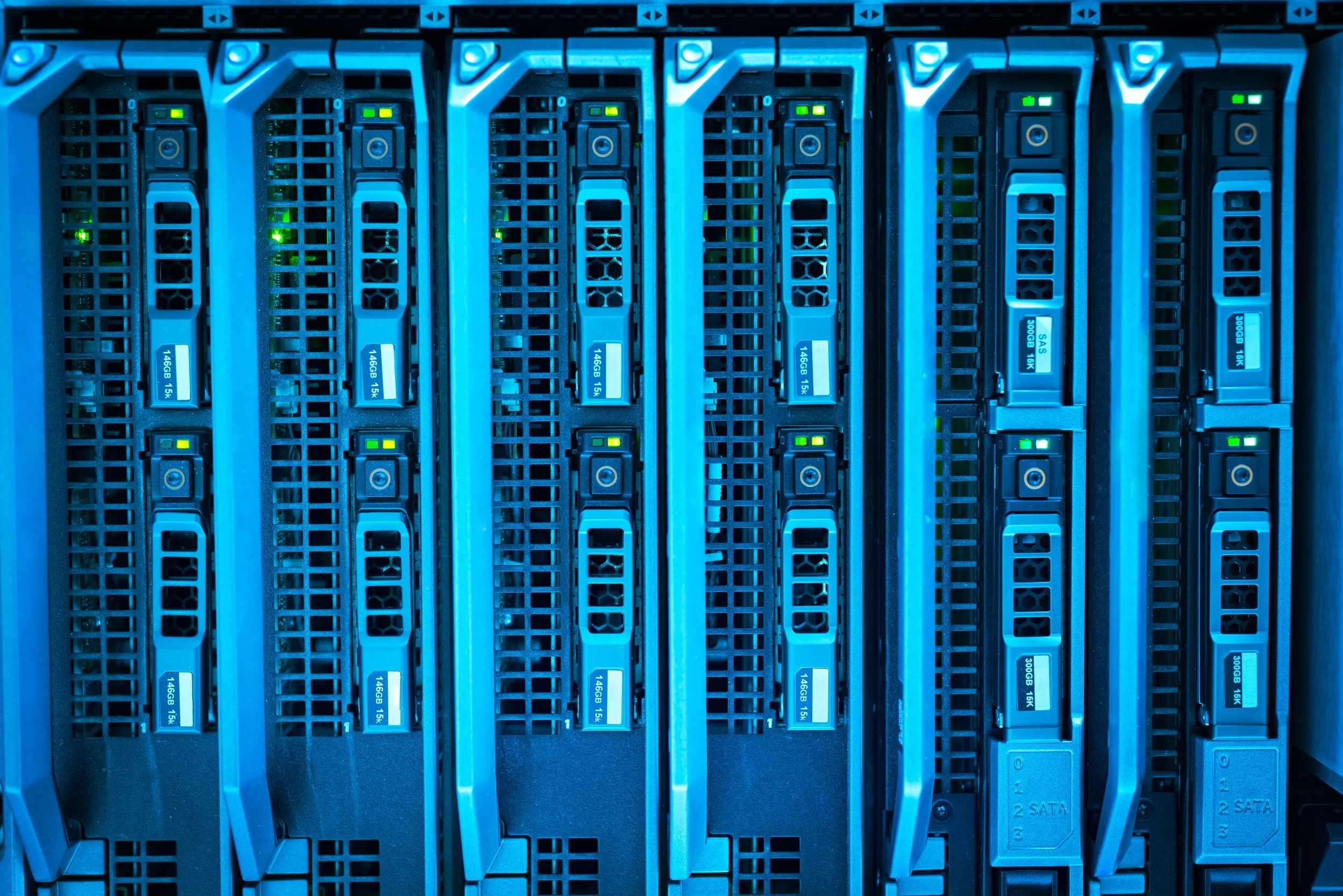 A close-up view of a server rack with multiple hard drives and data storage units, illuminated by blue LED lights.
