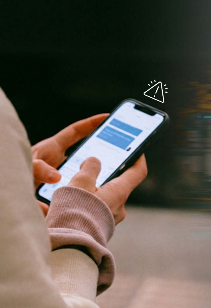 Person holding a smartphone, looking at a screen with messages. An alert icon appears near the phone.