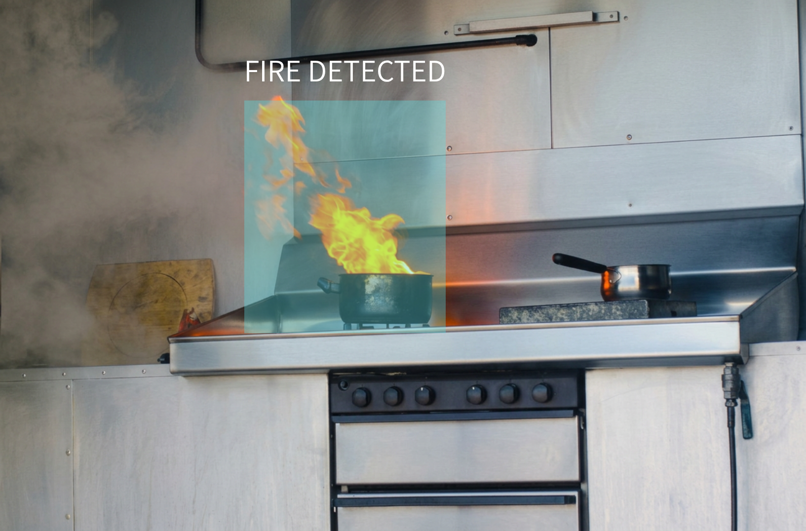 Kitchen with a stove and a pot on fire, with an overlay text that says "fire detected."