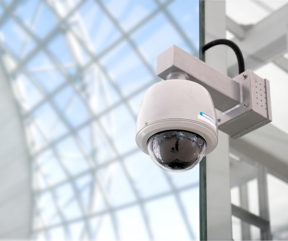 Security camera mounted on a wall with glass ceiling structure in the background