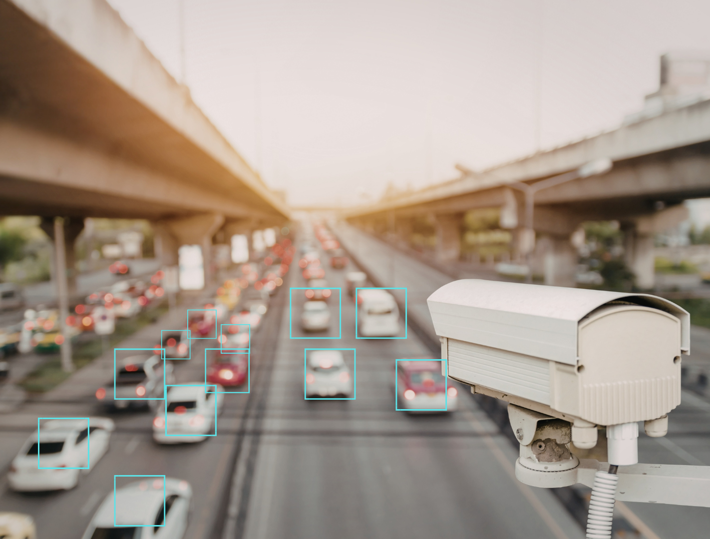 A traffic camera overlooking a busy multi-lane highway with numerous cars, with some areas highlighted by blue rectangles for identification.