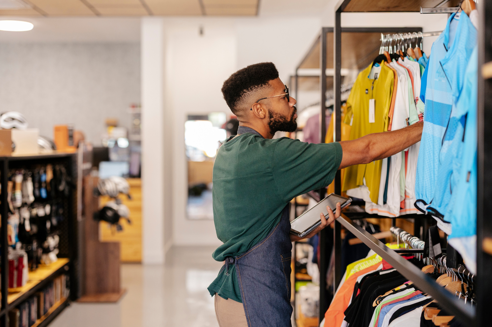 A retail employee working the storefront, checking the display of shirts.