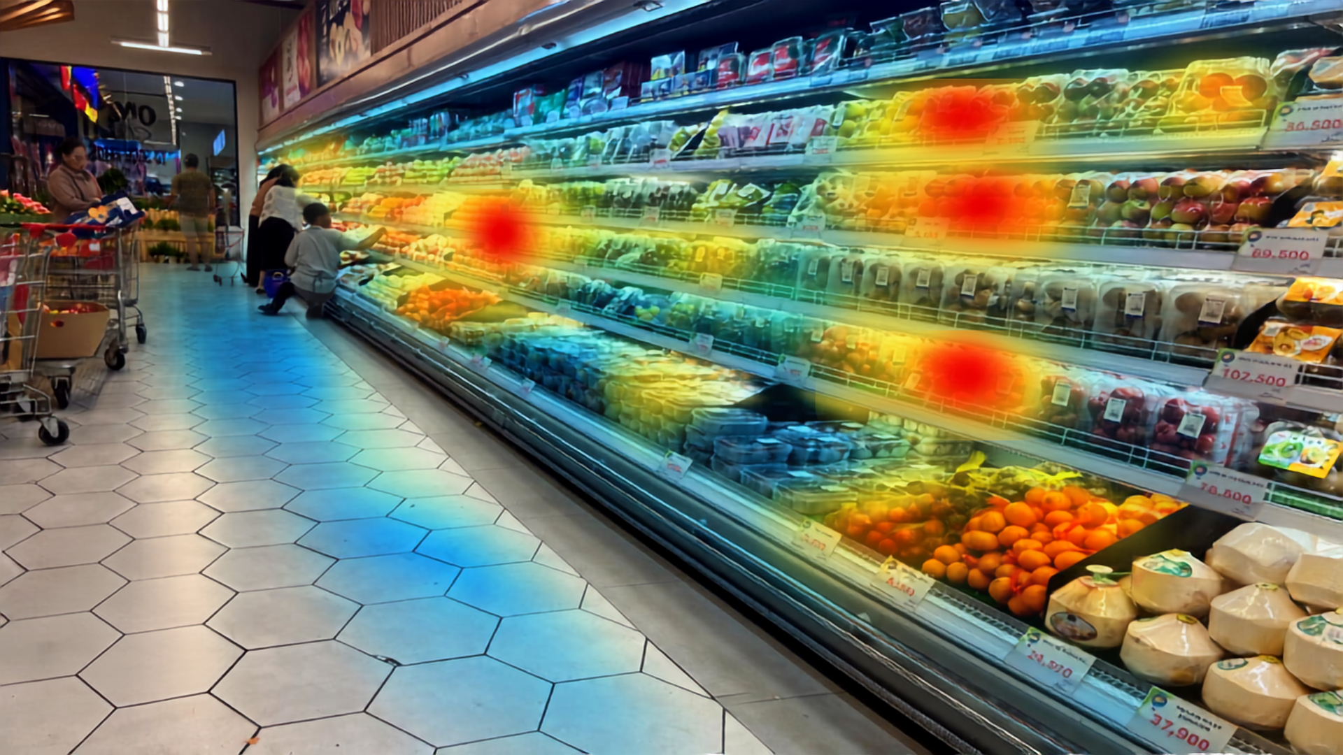Grocery store produce aisle with refrigerated shelves of fruits and vegetables and customers shopping, with a heat map overlay indicating high areas of interest on shelves.