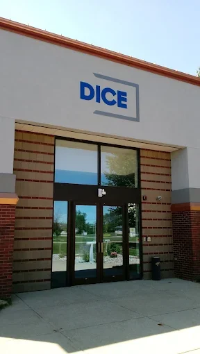 The entrance of a building with a sign that says "DICE" above the doorway, glass doors, and brick accents.