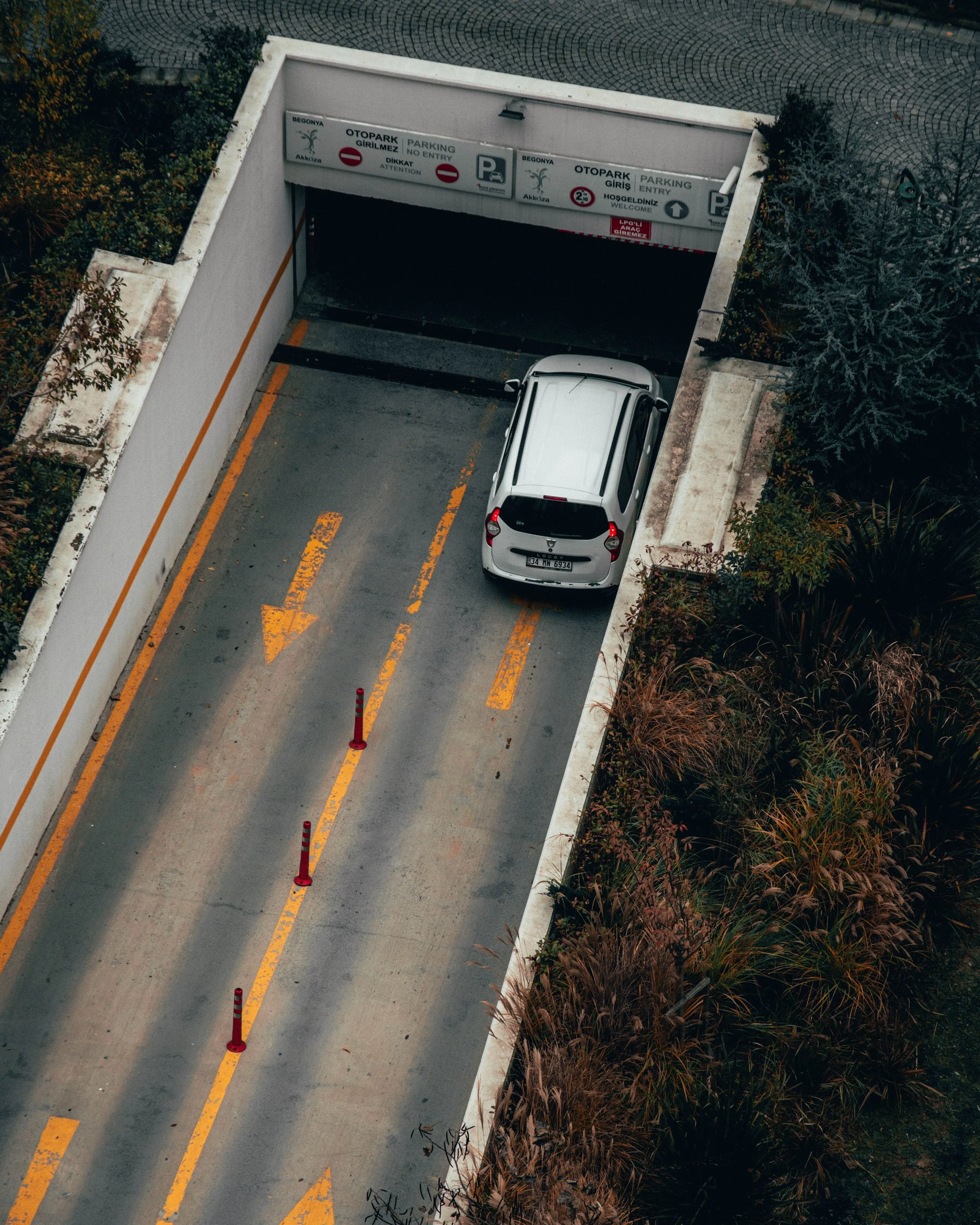 An entrance to a tunnel with arrows pointing which way each lane goes. A white car is entering the tunnel.
