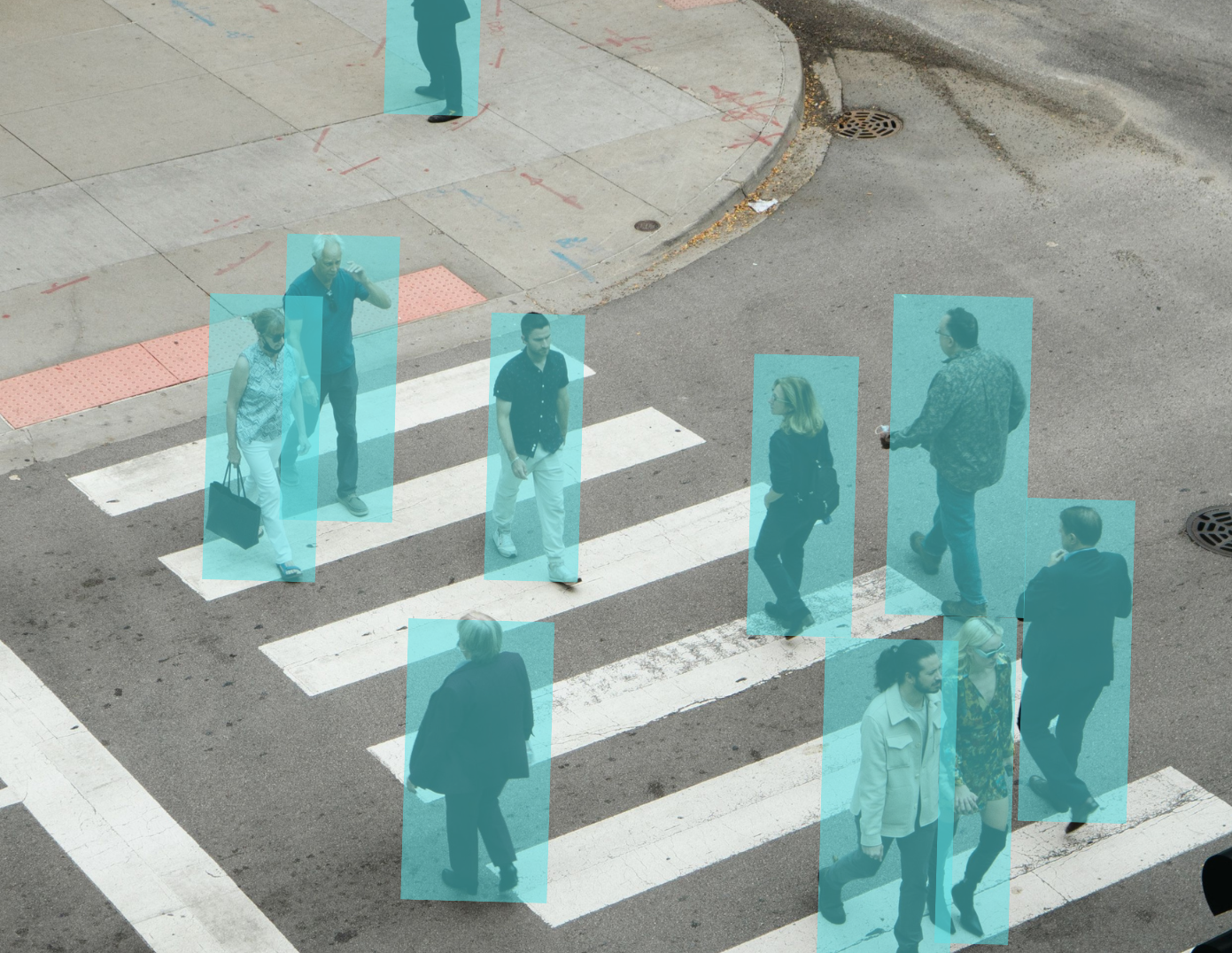 People walking across a crosswalk at an intersection, with an outline indicating pedestrian detection in an urban setting.