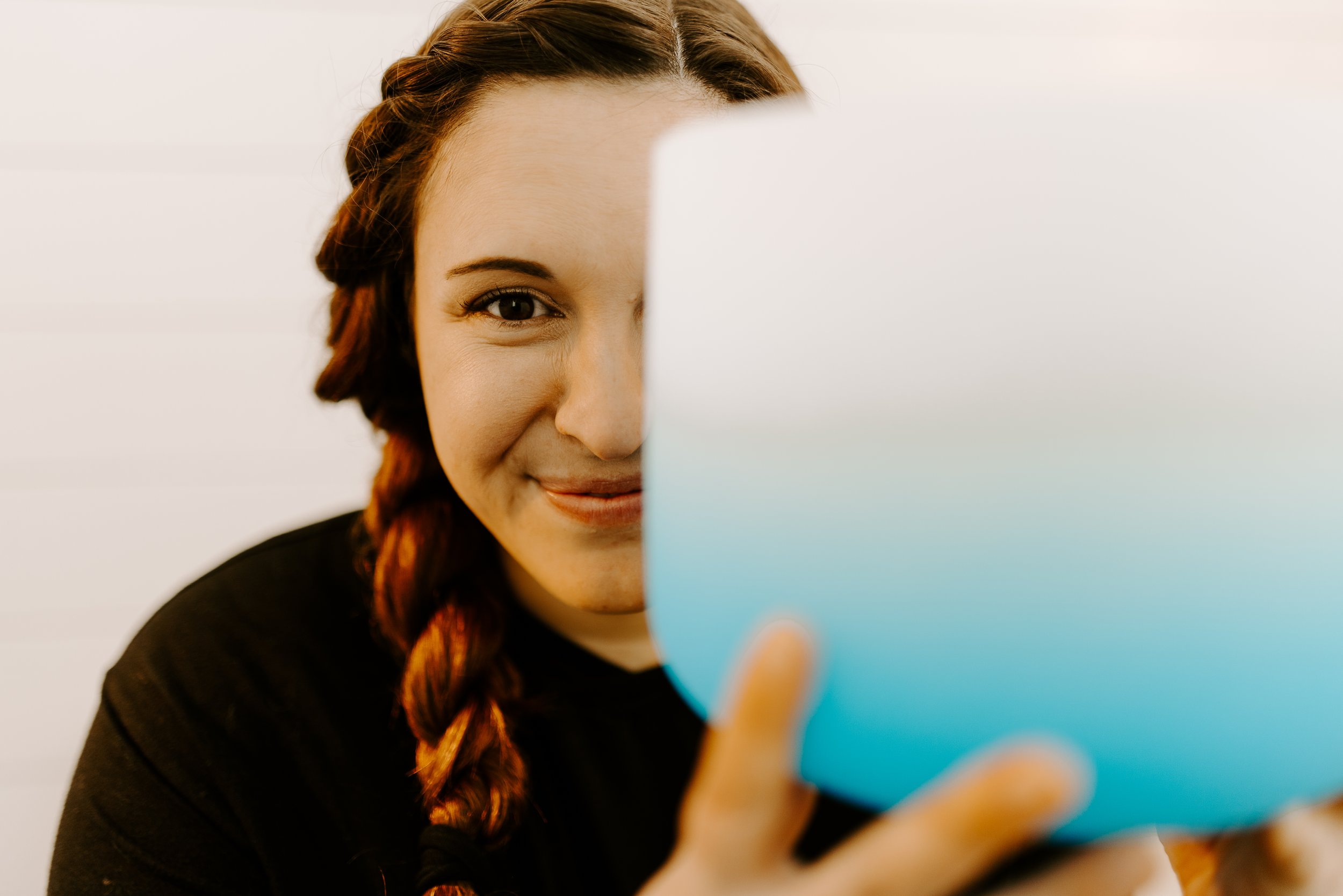 A woman with braided hair looking at a crystal singing bowl.