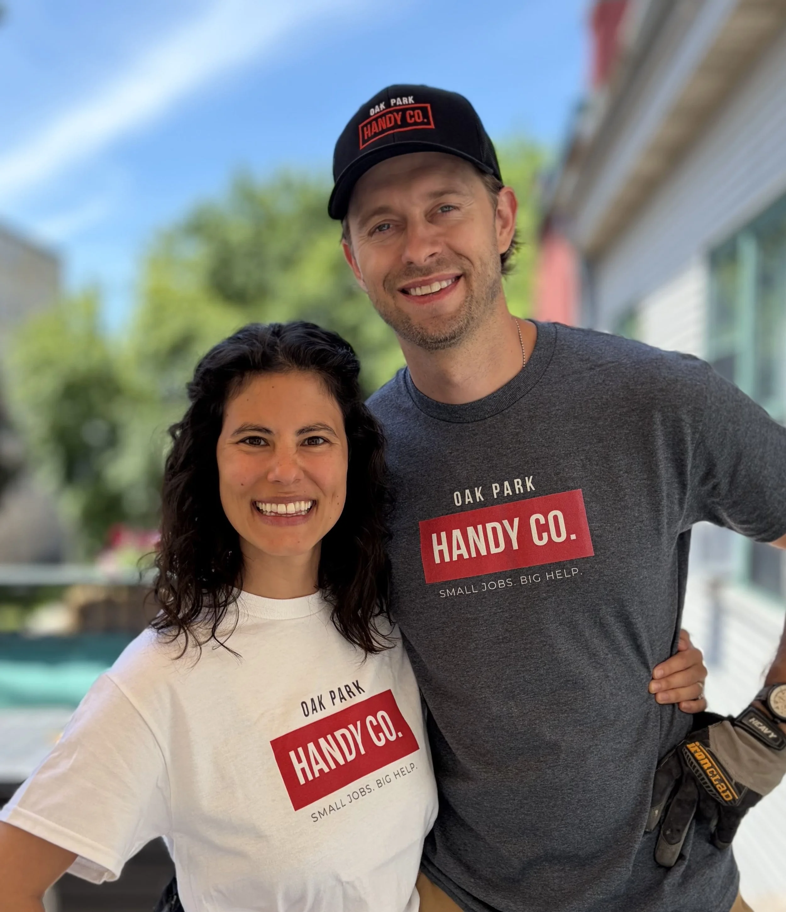 Owners of Oak Park Handy Co. Jess and Ben smiling at camera wearing Oak Park Handy Co. t-shirts