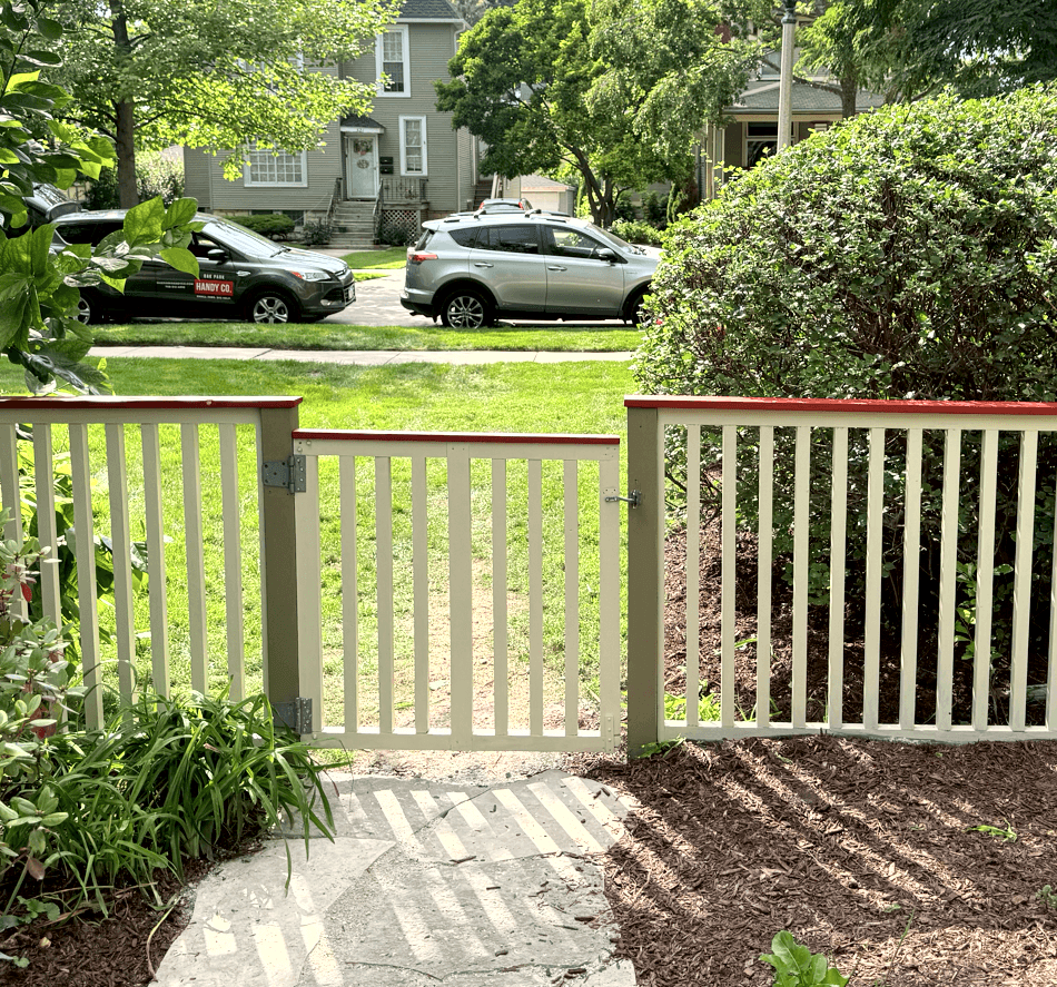 Repaired wooden fence in Oak Park painted white green and red by handyman