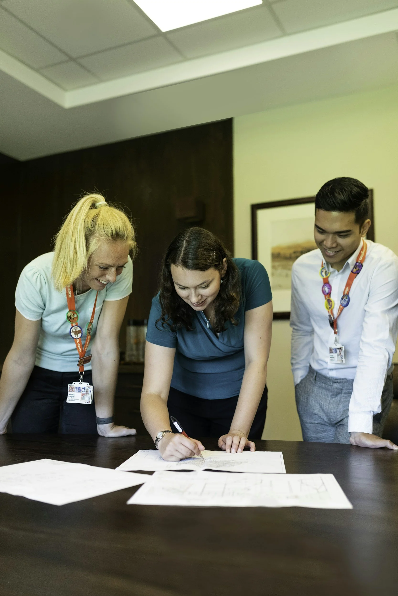 LW Fire Safety Professional Fire Safety Consultants are gathered around a table, looking at a Fire Risk Assessment Document. They appear to be in an office or conference room, smiling and engaged in a collaborative activity.