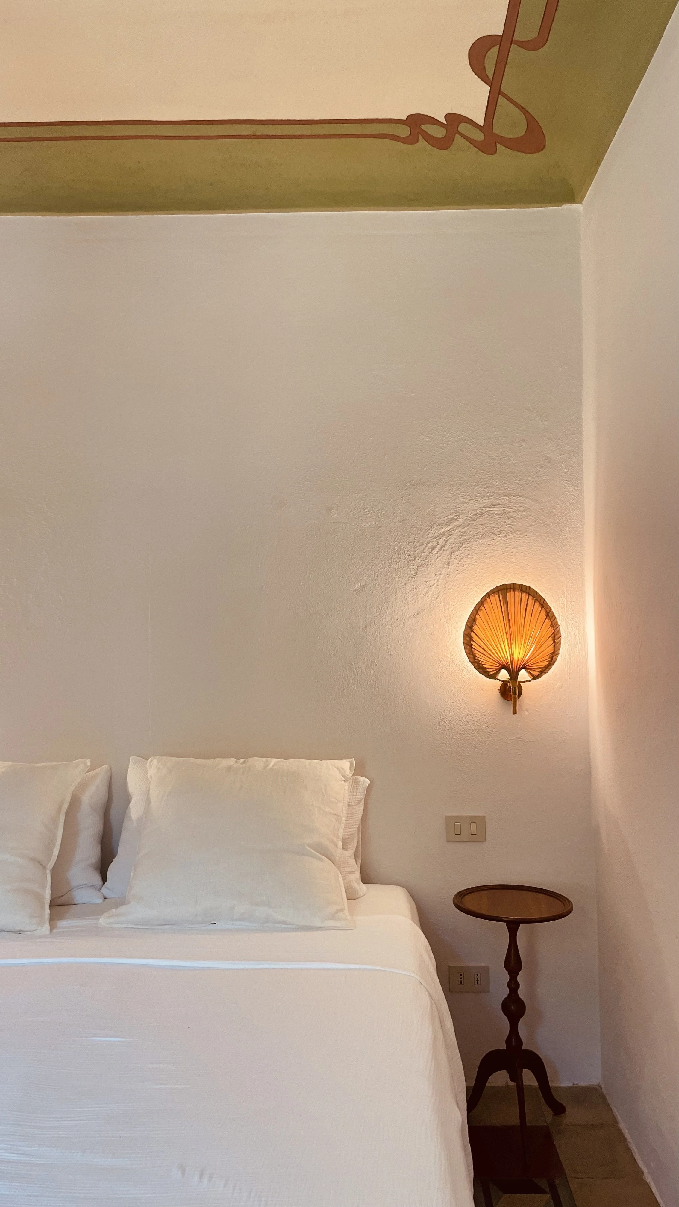 Elegant bed and sculptural wall light in the Fresco Rooms at Villa Oberti, a historic countryside villa in Piedmont