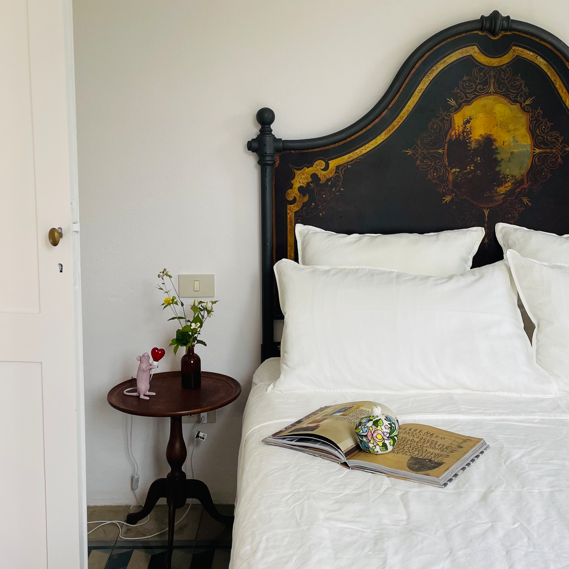 Elegant bedroom with antique painted headboard at Villa Oberti, a charming villa in Piedmont