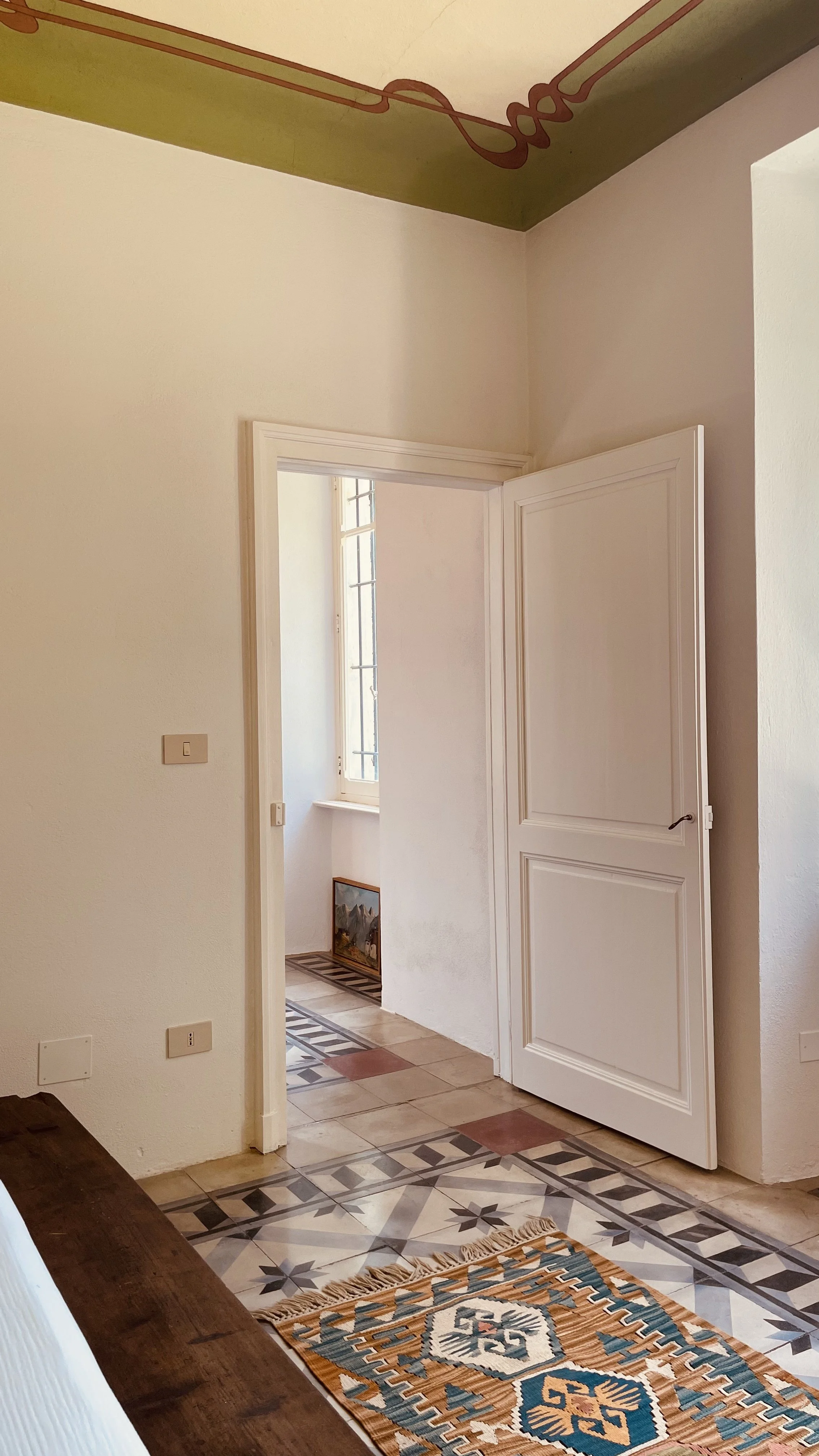 Original tiled floors and open doorway in the Fresco Rooms at Villa Oberti, a charming villa near Mondovì and the Langhe