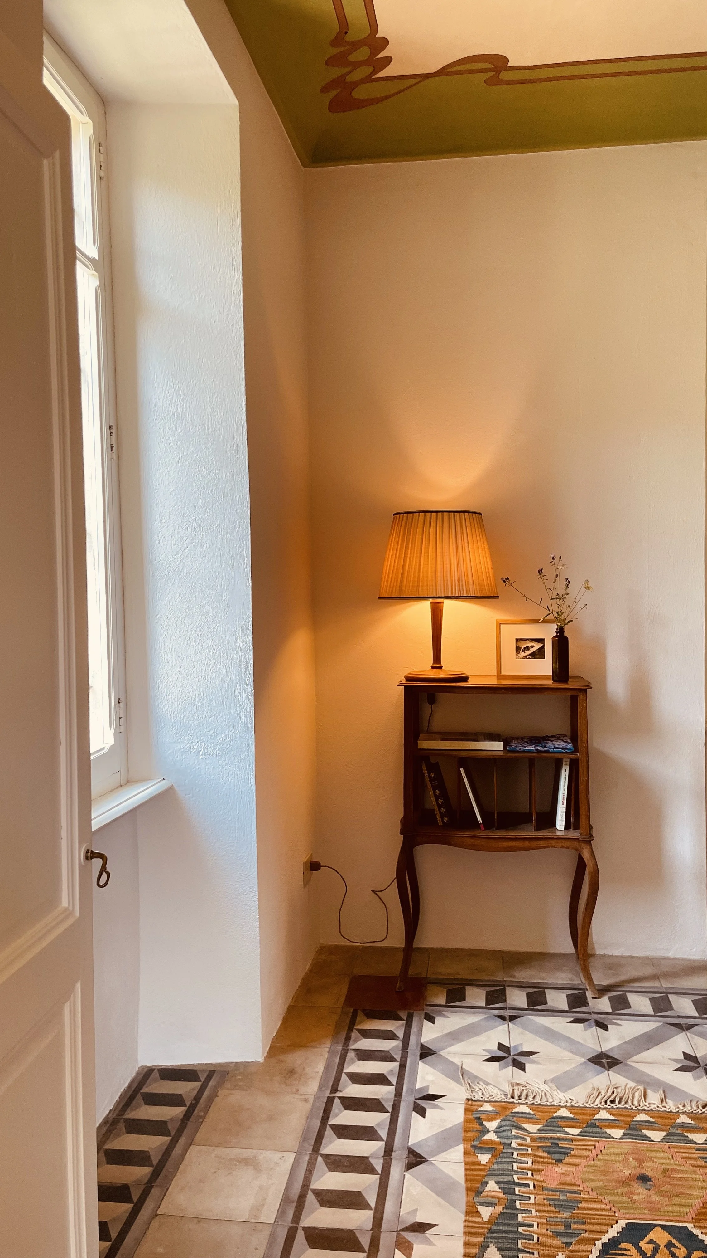 Quiet bedroom corner with vintage lamp and original tiled floor at Villa Oberti, a restored villa near Mondovì