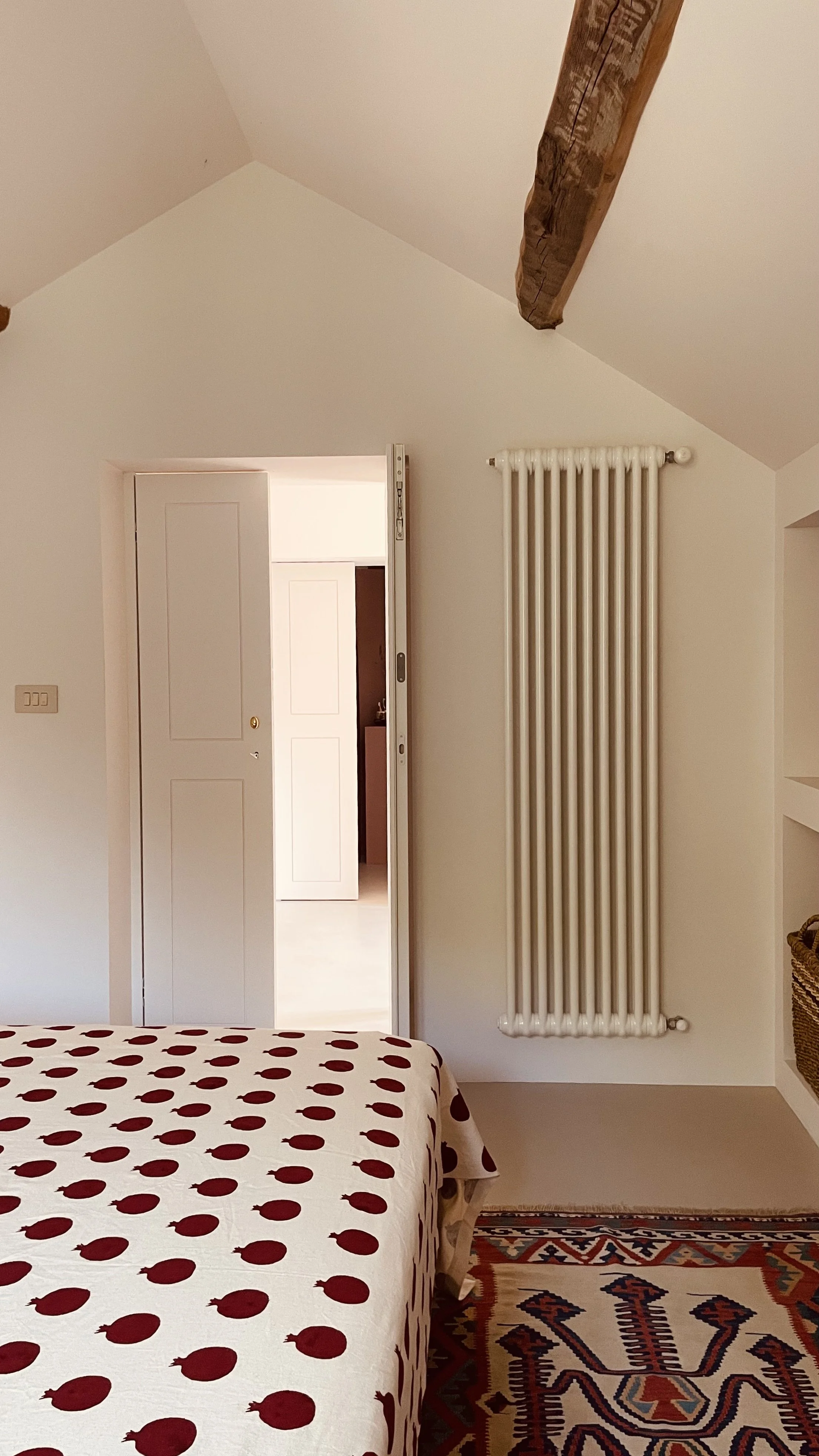 Attic bedroom with exposed wooden beam and kilim rug at Villa Oberti, a restored historic villa in Piedmont